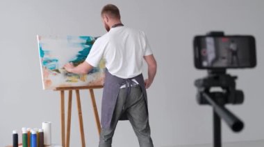 Deneyimli bir sanatçı çevrimiçi resim eğitimi yürütüyor. Bir sanat stüdyosunda video kaydı. Çağdaş sanatta teknoloji kullanımı