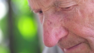 Çok yaşlı, kır saçlı bir büyükbaba akıllı telefonundan bir video izliyor. Eski ve teknoloji