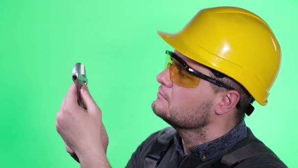 Young Worker Mechanic Helmet Glasses Green Background Studio Examines Work — Wideo stockowe