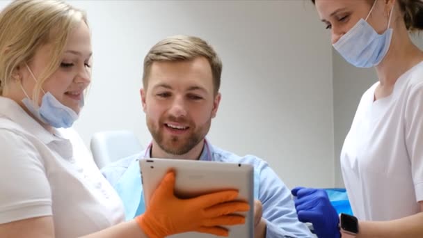 歯医者は患者と話し 歯の写真を見せる 近代的なヨーロッパのクリニックでの歯科治療 健康な歯 — ストック動画