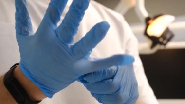 A close-up of a surgeon putting on blue medical gloves. The beginning of a surgical operation in a person.