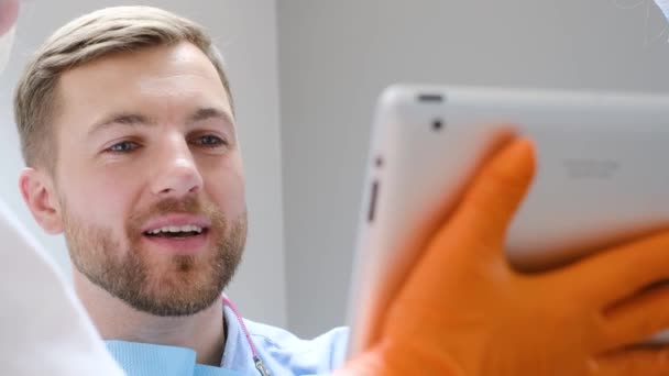 牙医与病人交谈 给他看牙齿的照片 在一个现代欧洲诊所接受牙科治疗 健康的牙齿 — 图库视频影像