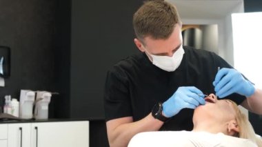 A dentist examines the teeth of a pensioner in the clinic. Close-up of an elderly woman during a dental examination. The doctor drills the tooth