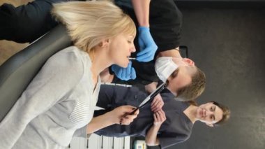 Vertical video, a dentist treats the teeth of a beautiful elderly woman. A retired woman at a dentists appointment. Installation of dental implants for the elderly