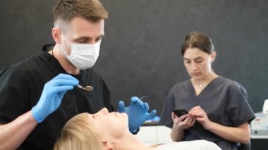 A young dentist examines the teeth of an elderly woman in the clinic. Close-up of an elderly woman during a dental examination. A modern European dental clinic