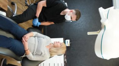 Vertical video, beautiful senior woman at the dentist having her teeth treated in the dentists office. A beautiful smile in old age