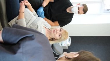 A beautiful elderly woman of European appearance at the dentists appointment. A retired woman treats her teeth in a dentists office. A beautiful smile in old age. Vertical video