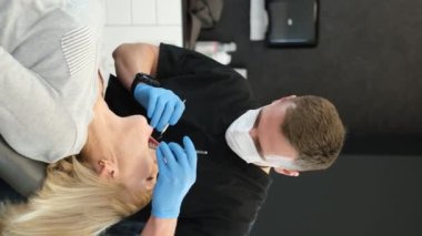 Vertical video, beautiful senior woman at the dentist having her teeth treated in the dentists office. A beautiful smile in old age
