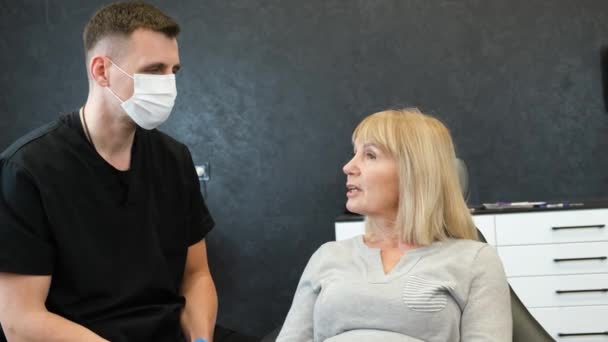 Starsza Kobieta Siedzi Gabinecie Dentystycznym Rozmawia Lekarzem Emerytka Poddana Leczeniu — Wideo stockowe