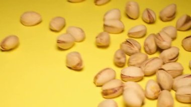 Pistachios fall on a yellow background, advertising video. Super Slow motion 200 frames