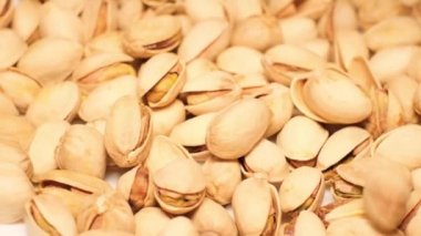 Pile of pistachio nuts with shell, close-up. Pistachio nuts. Rotation. Falling pistachios.