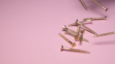 Self-tapping screws from steel on a pink background, metal screw, iron screw. Close up. Self-tapping screws made of stainless steel metal.