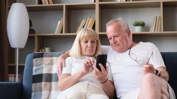 Modern Retired Couple Sitting Sofa Using Mobile Apps Grandfather Grandmother — Stok Video