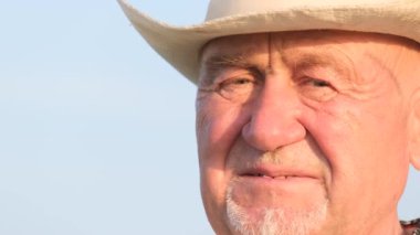 Close-up of an old face with wrinkles Grandfather in a hat against a blue sky. Pensioners. Elderly