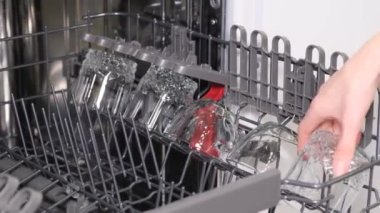 Yıkandıktan sonra bulaşık makinesinden parlak bir şekilde yıkanan bulaşıkları boşaltma işlemi sırasında kadın ellerine yakın çekim.