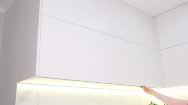 The housewife opened the drawer of the kitchen cupboard for dishes. Modern furniture in the kitchen room