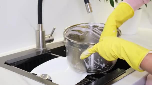 一个戴橡胶手套的女人用海绵洗金属罐的手 洗碗槽里洗碗的特写 — 图库视频影像