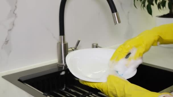 ゴム手袋の女性の手はスポンジで皿を洗う 台所の洗面台の食器類の閉鎖 — ストック動画
