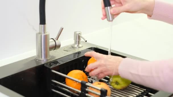 一个女人在厨房的水槽里用干净的自来水洗新鲜的水果 从细菌中清除水果 健康素食 — 图库视频影像
