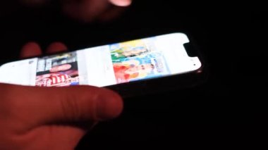 Close-up of a man looking at a mobile phone at night and browsing a social network. Touching your mobile phone with your fingers while using a mobile application