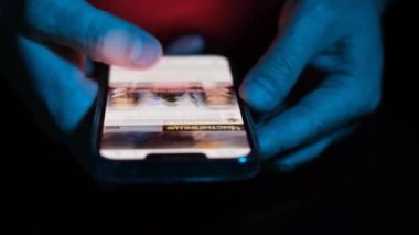 Bir erkeğin parmağı cep telefonundaki kaydırma uygulamasına dokunur. Sosyal ağlardan haberleri izleyin. Modern bir alet kullanarak.