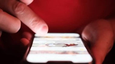 Close-up of using a modern smartphone, a man scrolls the news feed in a mobile phone. Use of social networks