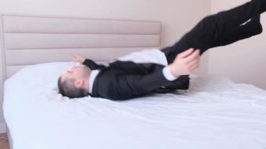 Ofis kıyafetleri içinde yorgun bir işadamı işten sonra yatakta yan gözle yatıyor. Ofiste çalıştıktan sonra yoruldum. 4k video