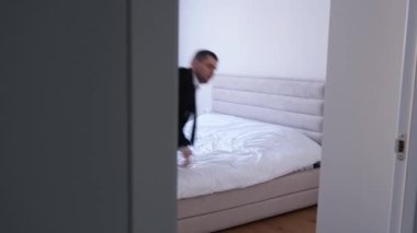 Yorgun bir adam, bir ofis çalışanı, soyunmadan yatağa girer. Yorgun bir adam yorucu bir iş gününden sonra. 4k video