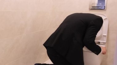 A young man in business clothes is experiencing symptoms of intoxication or illness, including vomiting and abdominal pain, and may have diarrhea. He needs to seek medical attention 
