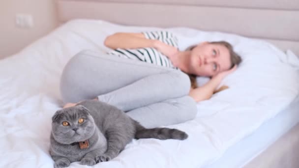 Przygnębiona Młoda Kobieta Leżąca Łóżku Pięknym Kotem Siedzącym Obok Niej — Wideo stockowe
