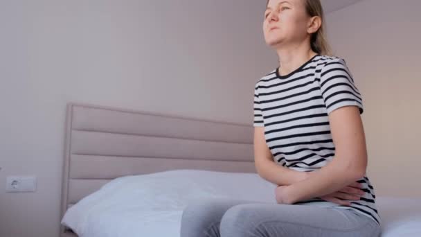 Kvinna Med Europeiskt Utseende Som Sitter Sängen Lider Magsmärtor Menstruationscykel — Stockvideo