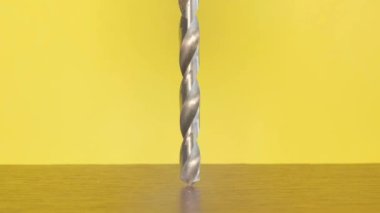 Construction tool for making holes. Drill rotation on a yellow background. The concept of carpentry made of wood. 4k video