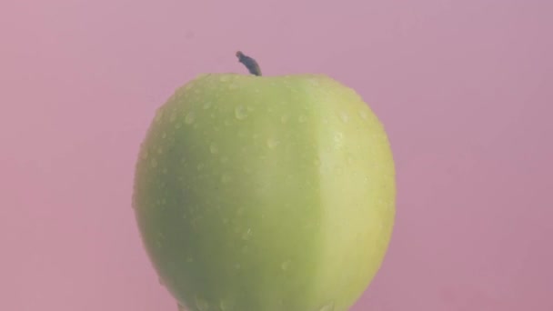 Rijp Groene Appel Met Waterdruppels Geïsoleerd Roze Achtergrond Hoge Kwaliteit — Stockvideo
