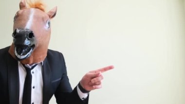 Komik at kafalı adam stüdyo arkaplanını işaret ediyor. At maskesi takmış bir adam. 4k video