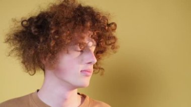 Close-up of a red-haired boys face on a light brown background. Positive emotions. Surprise. Accident. Surprise.