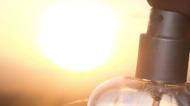 Mans hand spraying perfume dust at sunset, slow motion. Spraying aromatic perfume. 4k video