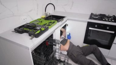 An American plumber uses tools to repair a leak in a sink. Work as a plumber.