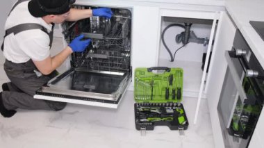 A professional plumber repairs the sink in the kitchen, the room lies under the sink. Plumbing services