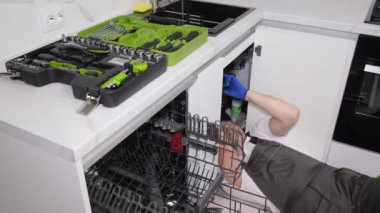 A craftsman during the installation of a dishwasher. Installation of household appliances in the kitchen room. 4k video