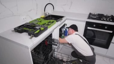 Top view of a master installing furniture and appliances in a kitchen room. Installing a dishwasher. 4k video