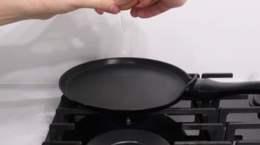 A mans hands break an egg into a hot pan. Preparing breakfast. Close up
