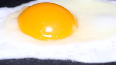 A close-up of an egg broken into a frying pan with oil for frying. The egg is fried on the stove from a pan with a high side.