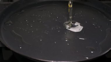 Slow motion of a delicious egg in a pan while cooking, surrounded by yellow olive oil. Cooking eggs close-up