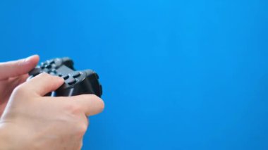 Close-up of a man playing on a portable game console on a blue background. Joystick for video games isolated on chromakey background.