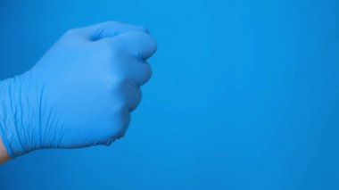 A doctors hand in rubber gloves counts with his fingers. Chromakey with a blue background.