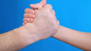Friendly handshake on a light blue background. Close up. 4k video