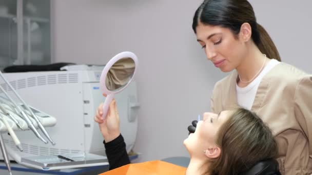 Paciente Jovem Está Sentado Uma Cadeira Dentária Uma Dentista Feminina — Vídeo de Stock