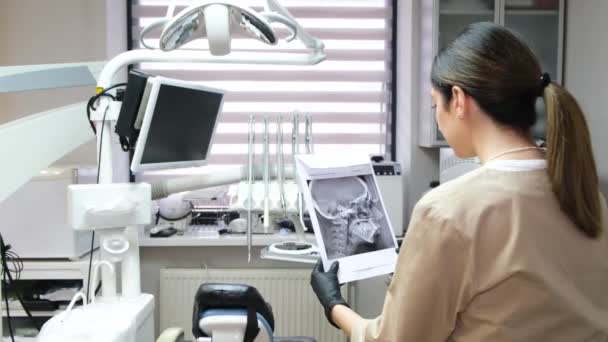 Uma Jovem Dentista Olha Para Uma Radiografia Dos Dentes Enquanto — Vídeo de Stock