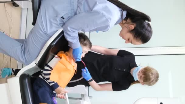 Positive Smiling Female Dentist Assistant Treating Little Boys Teeth Childrens — Stock video