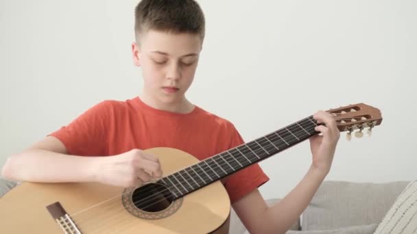 Młody Facet Gra Gitarze Swoim Pokoju Siedzi Kanapie Namiętnie Delektuje — Wideo stockowe